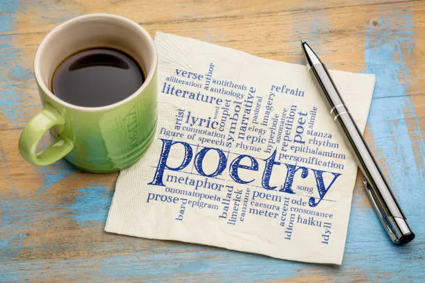 Cup of coffee and a napkin with "Poetry" printed, beside an ink pen